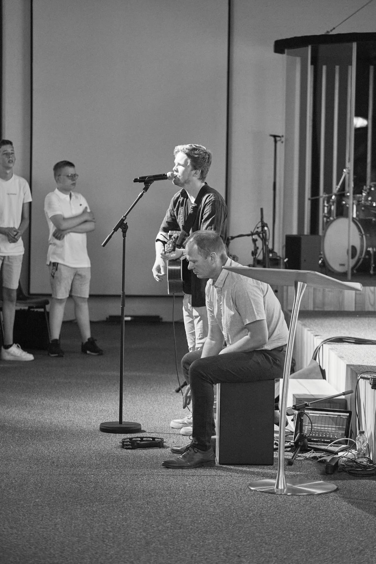 Worshipleider met gitaar en muzikant tijdens de aanbidding in de zaal