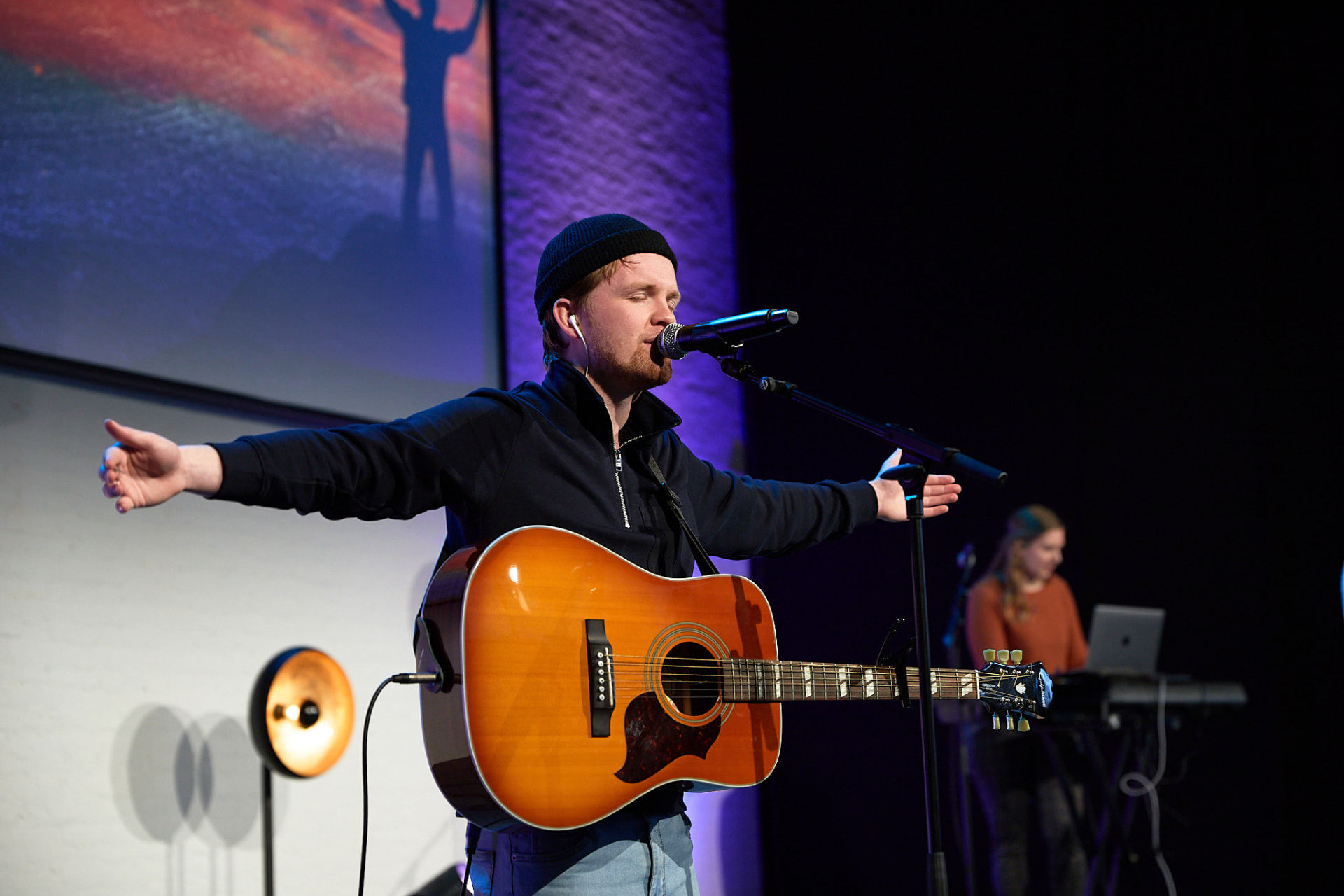 Worshipleider met gitaar en open armen tijdens de aanbidding