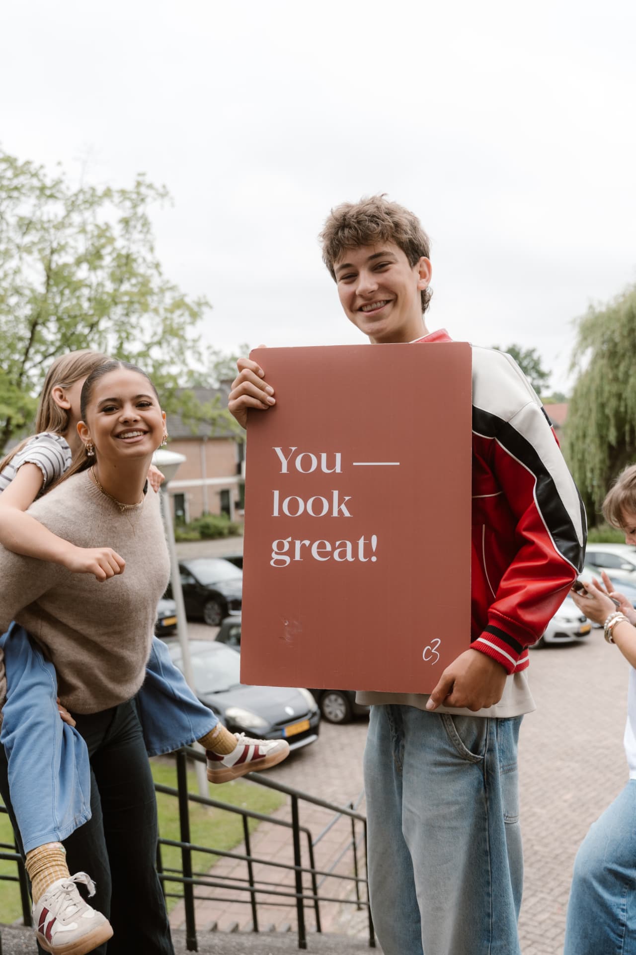 Jongeren met een bord met de tekst You look great